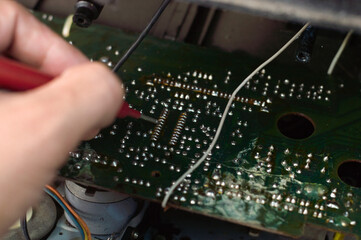 Repairman repairing electronic circuit board with red pen, close-up