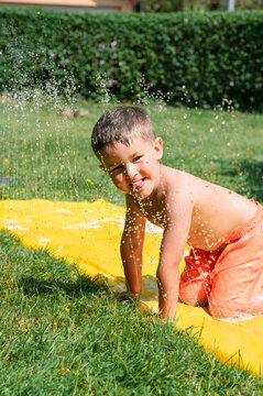 Boy playing on water slide in garden
