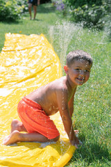 Little boy splashing water on water slide