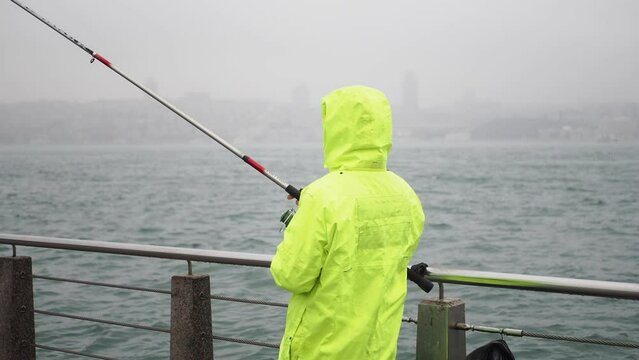 Fisherman in yellow rain coat spinning reel ,