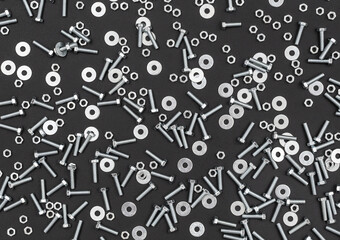 Bolts with nuts and washers on black background. Top view. Industrial background.