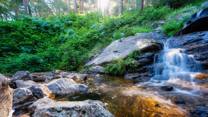 Crystal clear water that falls between large rocks in an enchanted forest of the Sierra de...