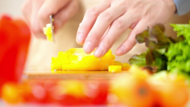 パプリカを切る若い男性　料理イメージ