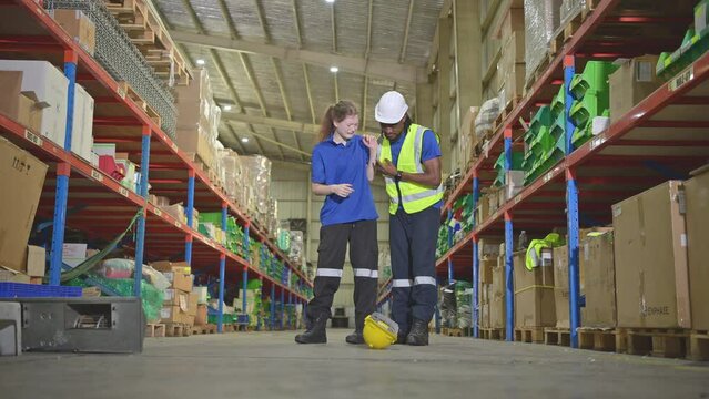 A warehouse worker consoles and helps a female worker who cries out in pain after a leg accident in a large warehouse