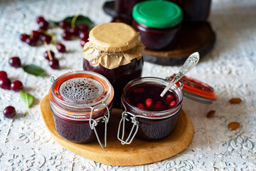 Preparation for winter: cherry jam in jars. Sweet dessert: jam made of cherries in jars on a white background. Close-up