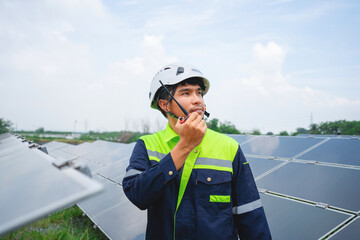 Portrait of an Asian male worker in a helmet checking the quality of a modern solar battery. clean...