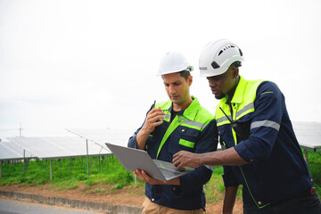 Two young engineers in safety clothes inspect solar panels. solar energy clean energy concept alternative energy.