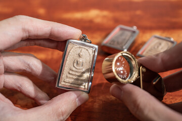Using a loupe to see the detail on an old Thai Buddha amulet