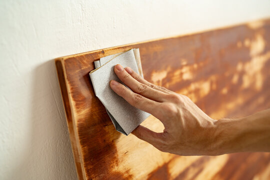 Scrubbing wood panel with sandpaper