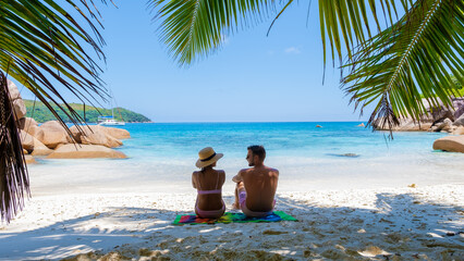 a young couple of men and women on a tropical beach during a luxury vacation in the Seychelles. Tropical beach Anse Lazio Praslin Seychelles Islands - obrazy, fototapety, plakaty