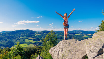 Happy woman standing on cliff,  Morvan in France- Travel, freedom, achievement concept