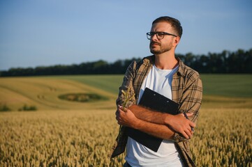 Naklejka na ściany i meble Farmer In Wheat Field At Harvest