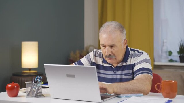 Home office worker old man working on laptop stressed.