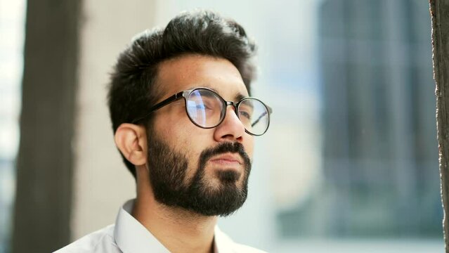 Side view Close up portrait of a confident businessman in a white shirt and glasses looking to the side. Handsome serious bearded male standing on the street outside Thoughtful developer IT specialist