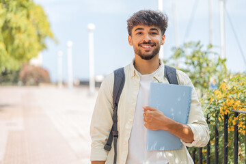 Young student Arabian man at outdoors smiling a lot