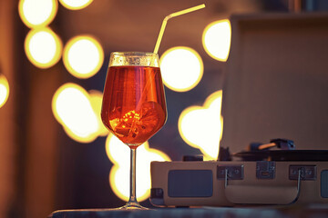 Orange spritz aperol cocktail on table of summer terrace. Wine glass of spritz aperol and turntable on summer terrace in the evening.
