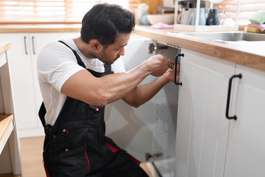 Asia man workers in uniform fixing  furniture and equipment in the kitchen at home