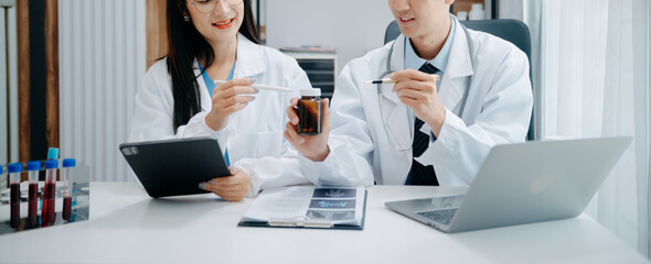 Medical team having a meeting with doctors in white lab coats and surgical scrubs seated at a table...