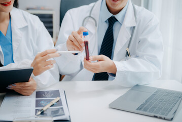 Medical team having a meeting with doctors in white lab coats and surgical scrubs seated at a table...