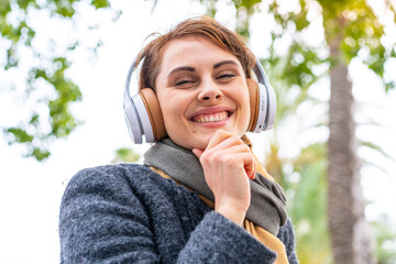 Brunette woman listening music with headphones at outdoor