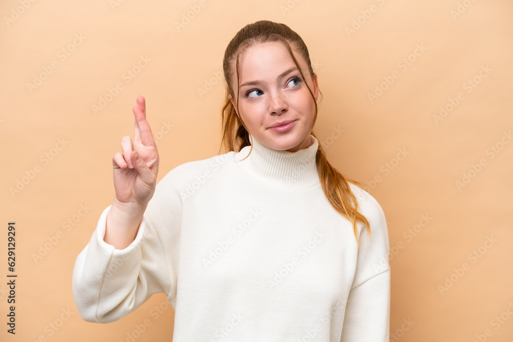 Canvas Prints Young caucasian woman isolated on beige background with fingers crossing and wishing the best