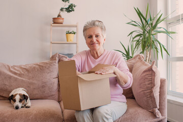 Smiling older adult mature woman customer unpacking parcel