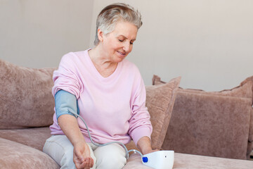 Senior elder woman measure high low blood pressure test holding using tonometer