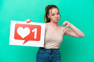 Young caucasian woman isolated on green background holding a placard with Like icon with proud gesture