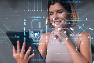 Smiling businesswoman in casual wear holding tablet device touching it at office workplace. Concept of distant work, business education, information technology. Lock icons hologram