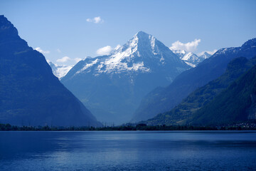 Scenic mountain panorama with Lake Lucerne in the foreground and Swiss village Flüelen in the background on a sunny spring day. Photo taken May 22nd, 2023, Lake Lucerne, Switzerland.