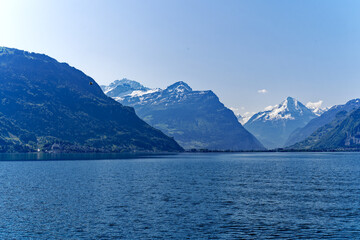 Fototapeta na wymiar Scenic mountain panorama with Lake Lucerne in the foreground and Swiss village Flüelen in the background on a sunny spring day. Photo taken May 22nd, 2023, Lake Lucerne, Switzerland.