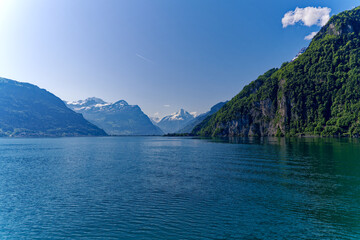 Scenic mountain panorama with Lake Lucerne in the foreground and Swiss village Flüelen in the background on a sunny spring day. Photo taken May 22nd, 2023, Lake Lucerne, Switzerland.