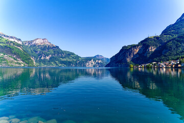 Fototapeta na wymiar Scenic view of Lake Lucerne with Swiss Alps and mountain panorama seen from lakeshore of village Flüelen on a sunny spring day. Photo taken May 22nd, 2023, Flüelen, Switzerland.