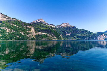 Scenic view of Lake Lucerne with Swiss Alps and mountain panorama seen from lakeshore of village Flüelen on a sunny spring day. Photo taken May 22nd, 2023, Flüelen, Switzerland.