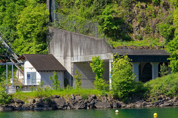 Isleten village with industrial building and road tunnel at lakeshore of Lake Lucerne on a sunny spring day. Photo taken May 22nd, 2023, Isleten, Canton Uri, Switzerland.