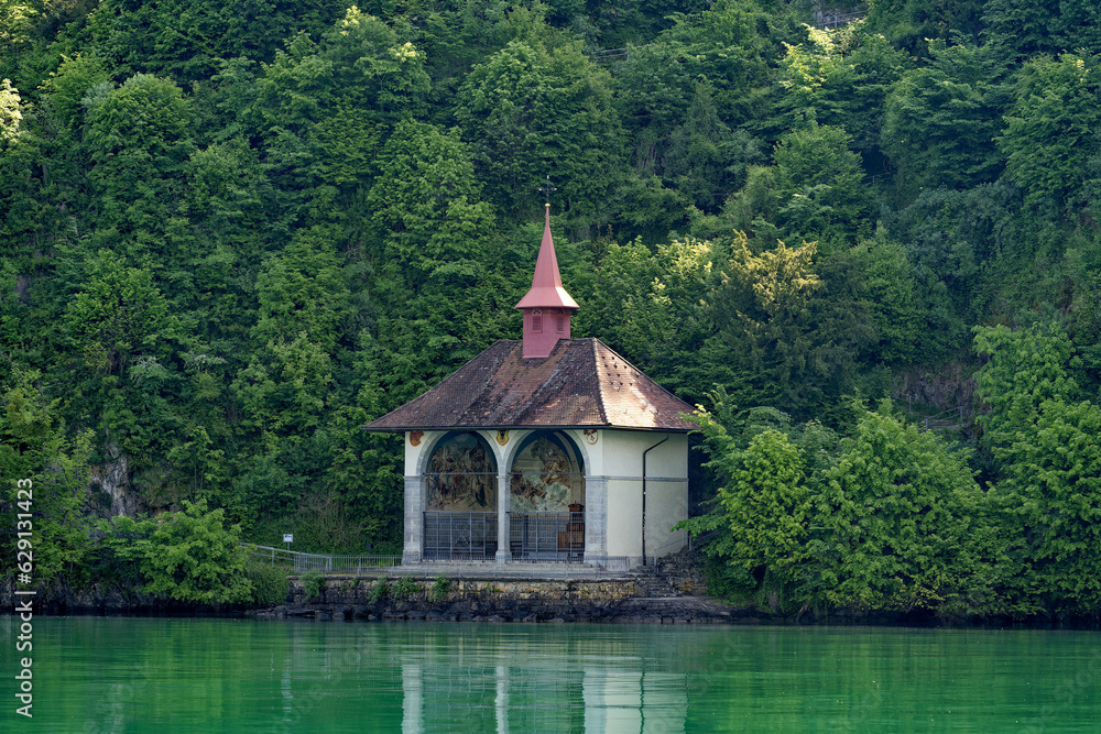 Wall mural Famous Tell's Chapel at lakeshore of Lake Uri on a sunny spring day with woodland in the background. Photo taken May 22nd, 2023, Sisikon, Canton Uri, Switzerland.