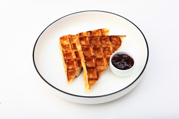 Waffles with jam in white plate on white background. Classic waffles for breakfast. Copy space. Isolated object.