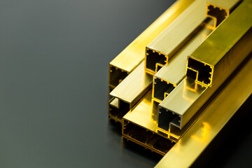 Gold color aluminum profiles on black background, copy space, used in the construction industry, interior trim, aluminum door frame, aluminum price increase