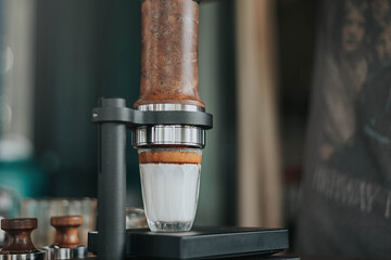 Professional barista making fresh coffee from ARAM espresso machine. Close up of hands barista brewing dirty coffee by handmade coffee machine in counter coffee shop.