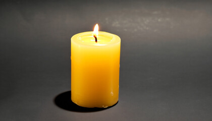 Burning yellow candle isolated on black background.