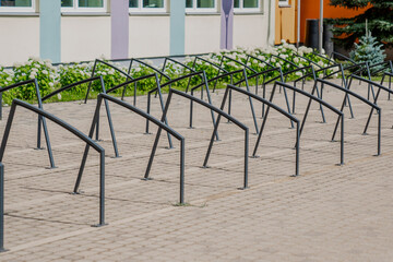 Fototapeta premium Black metal bike parking metal frames next to a school. Creative stylish design for bicycles