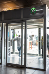 Smoking room or cabin at departure hall of airport with unrecognized people smoking within