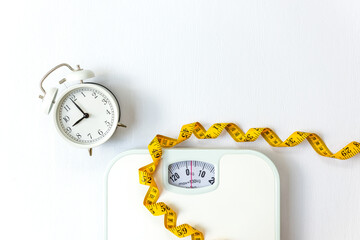 Weight loss control planning.  White scale and measuring tape and timing alarm clock for body...