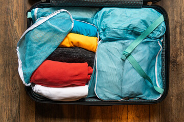 Clothes rolled and packed in small bags in suitcase to organize and save space during travel