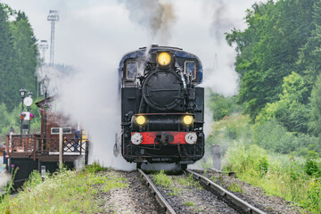 Fototapeta na wymiar Retro steam train arrives to the platform.