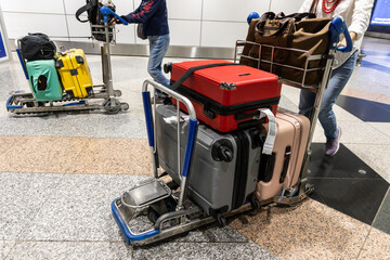 Traveller pushing trolley with luggages and bags in airport terminal