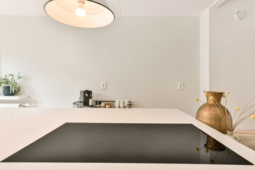 a kitchen with white counter tops and black counterstop in the center of the room is a pot of yellow flowers