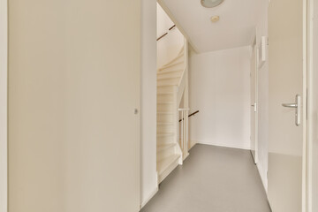 an empty hallway with white walls and grey flooring the room is well lit by daylight light from the window