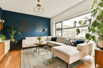 a living room with blue walls and white furniture, including a large plant in the corner of the...