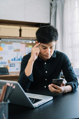 Portrait of a young man thinking sitting at his desk in the office.